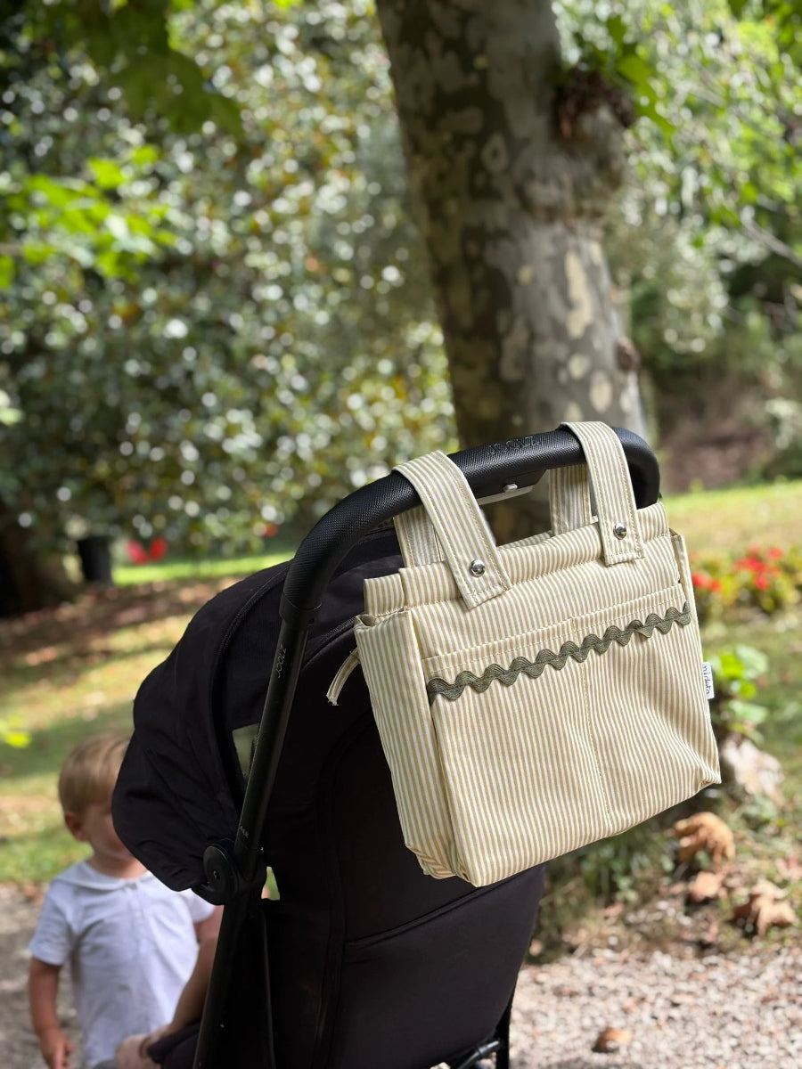 Beige baby stroller bag attached to a stroller in a park