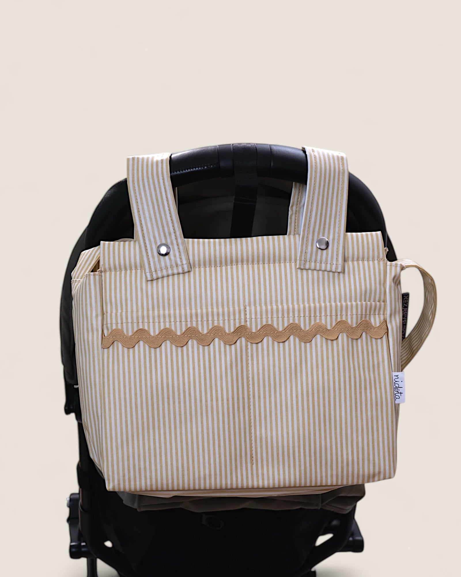 Striped stroller bag attached to a stroller on a beige background