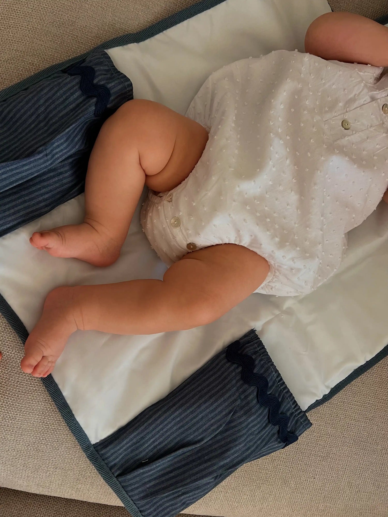baby laying on a changing mat with blue pockets for diapers and wipes