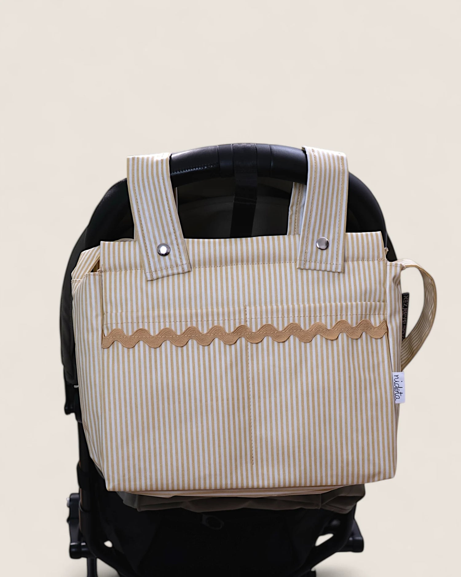 Striped stroller bag attached to a stroller on a beige background