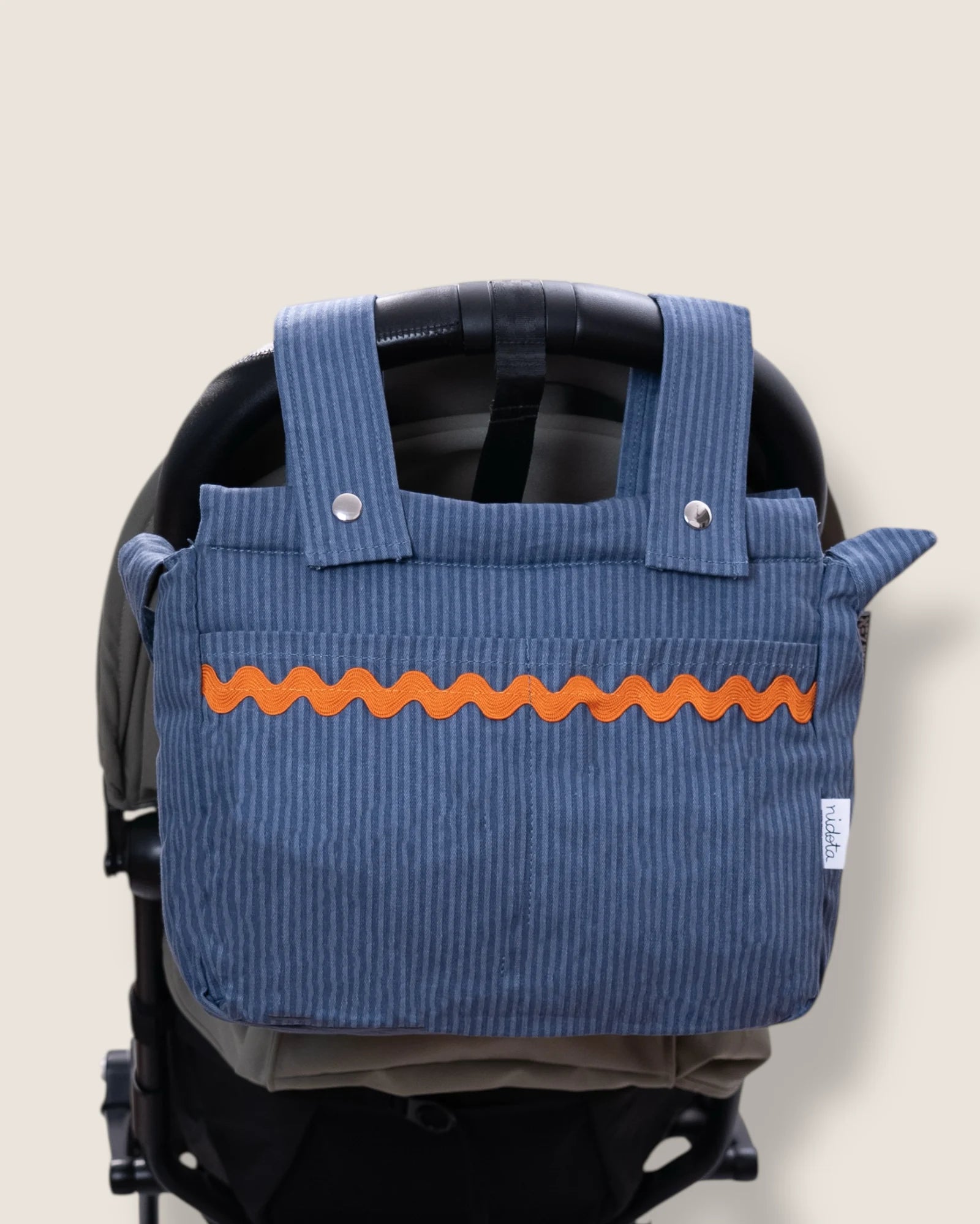 striped Blue stroller organizer bag with orange accents on a beige background