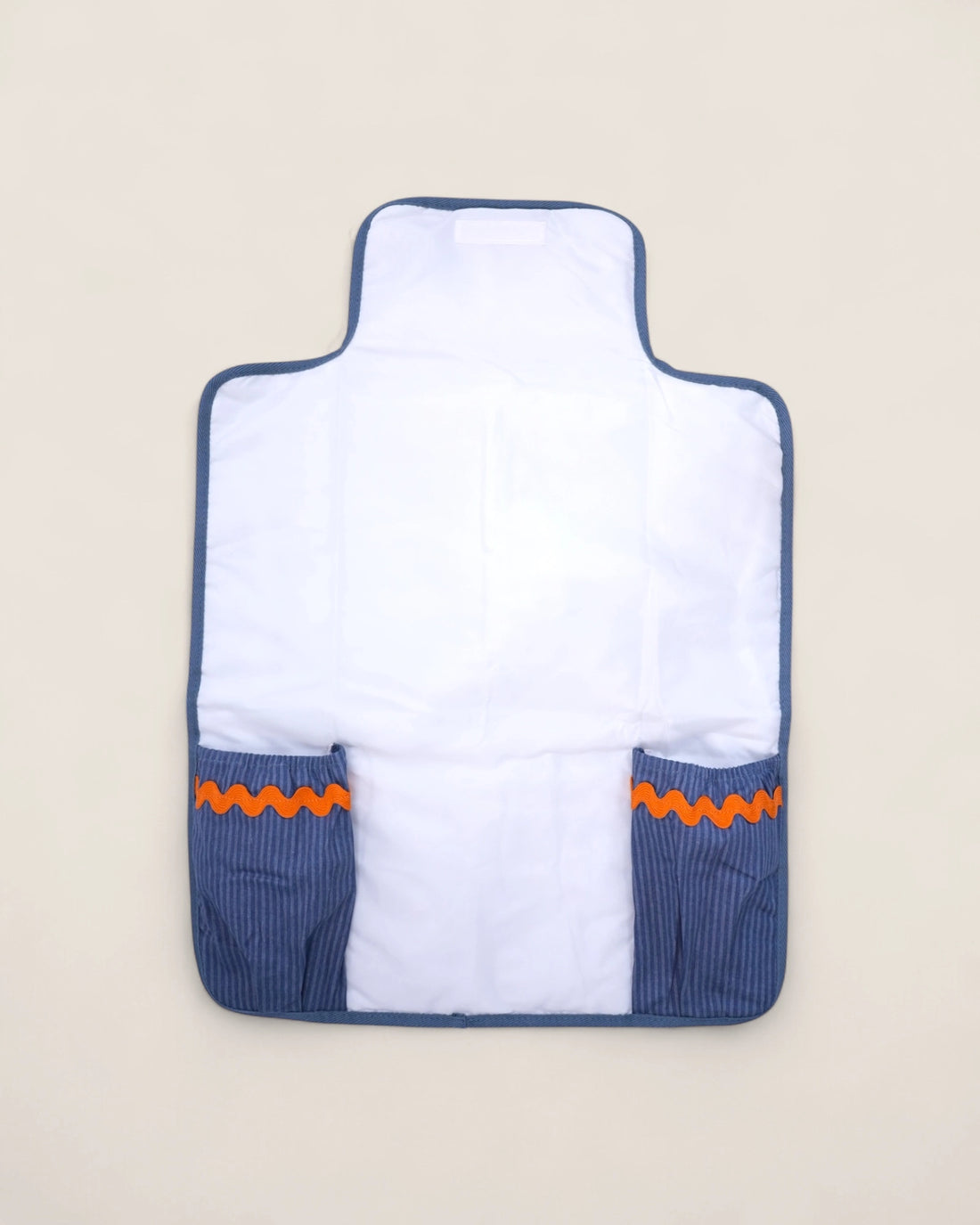 baby changig mat opened, with blue pockets for diapers and wipes and a waved orange design