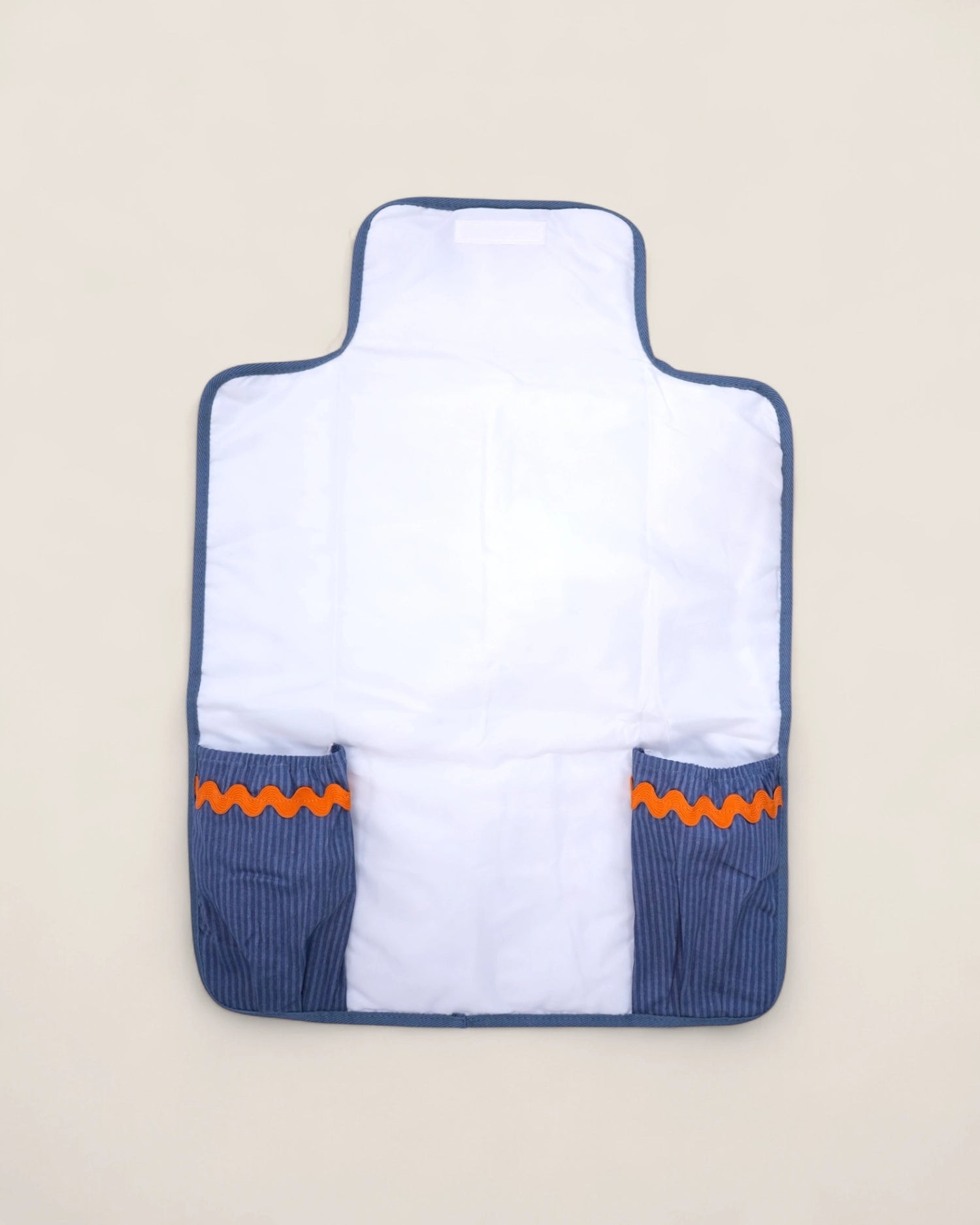 baby changig mat opened, with blue pockets for diapers and wipes and a waved orange design