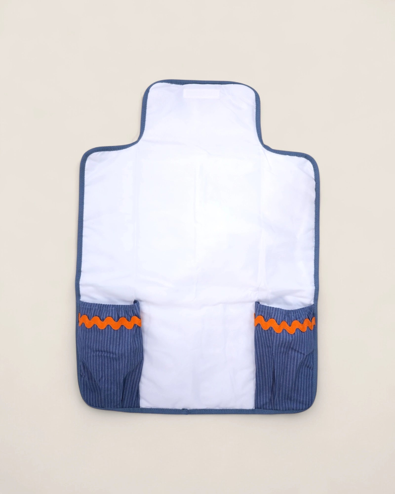baby changig mat opened, with blue pockets for diapers and wipes and a waved orange design