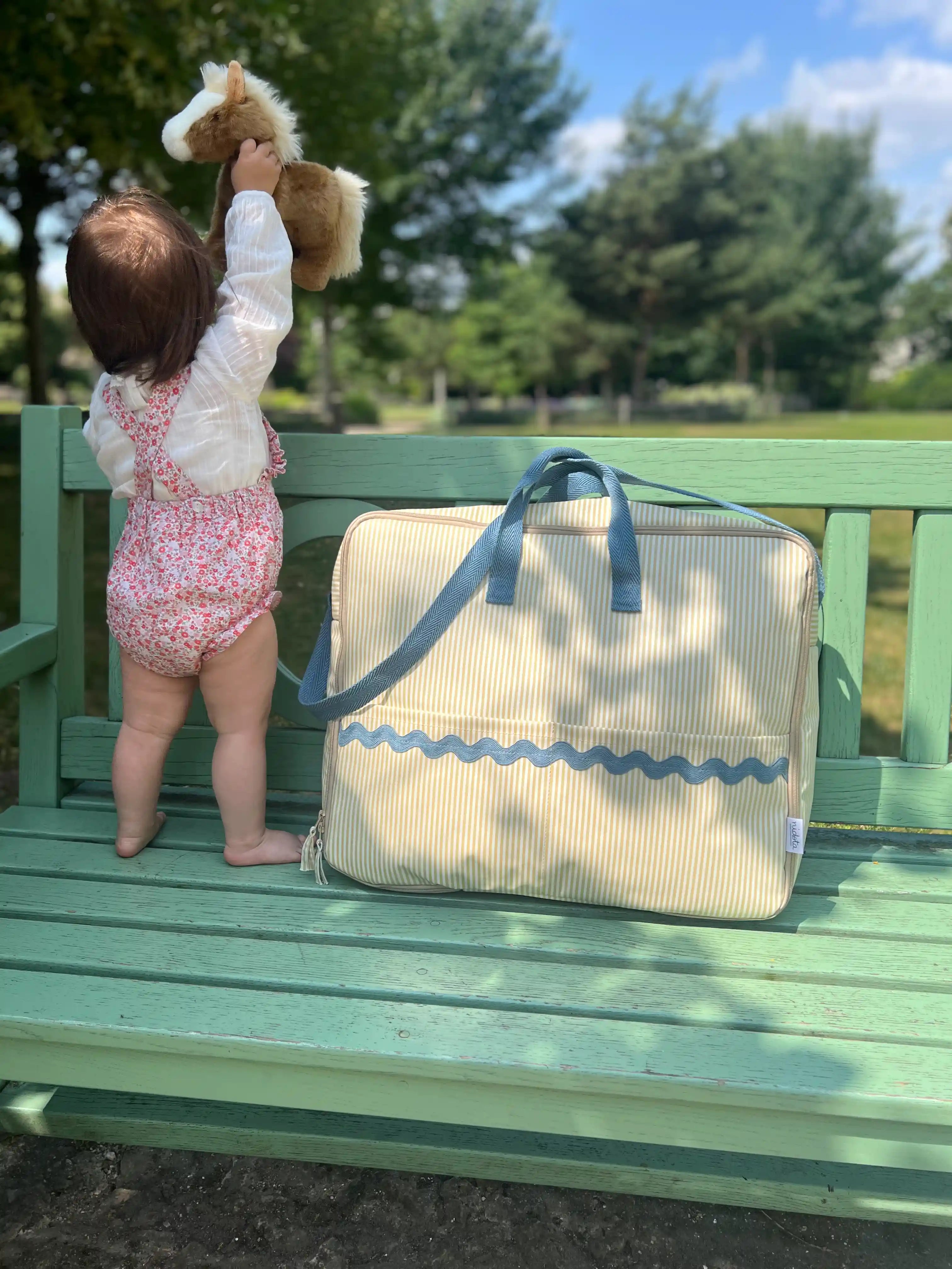maternity bag suitcase in a park with baby next to it