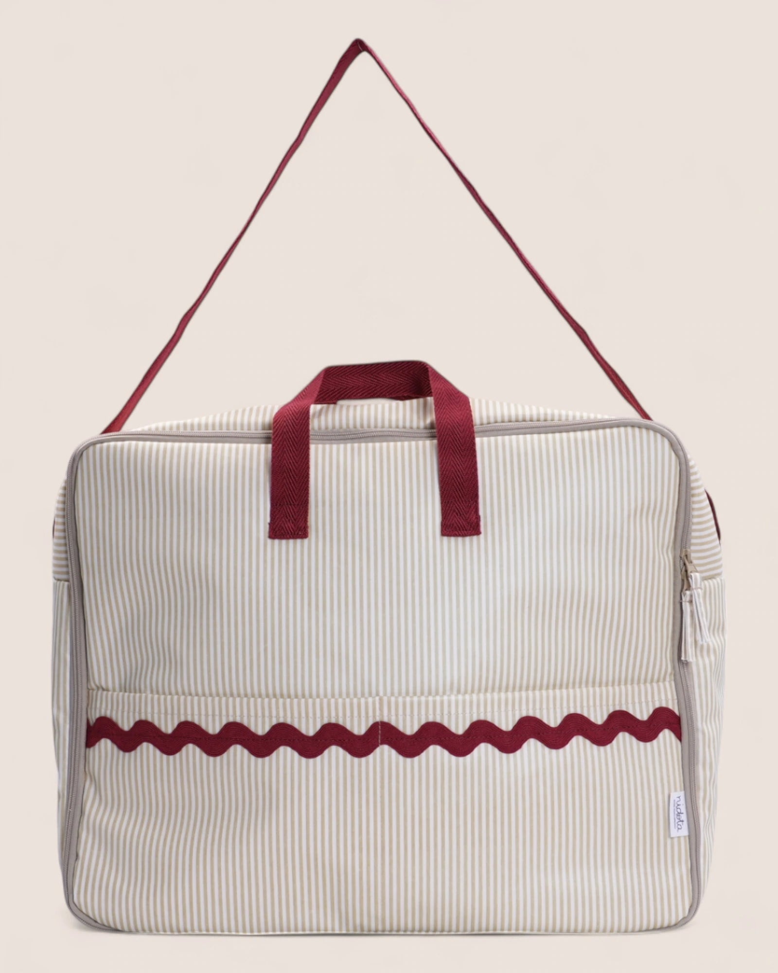 Beige and red striped maternity suitcase with handles on a beige background