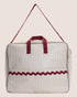 Beige and red striped maternity suitcase with handles on a beige background
