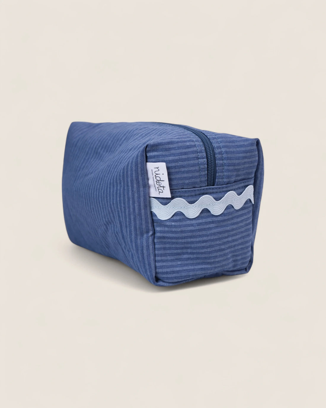 Blue striped toiletry bag with a light blue wave design on a beige background