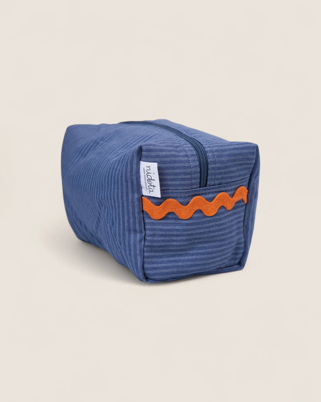 Blue striped toiletry bag with orange waved design on a beige background
