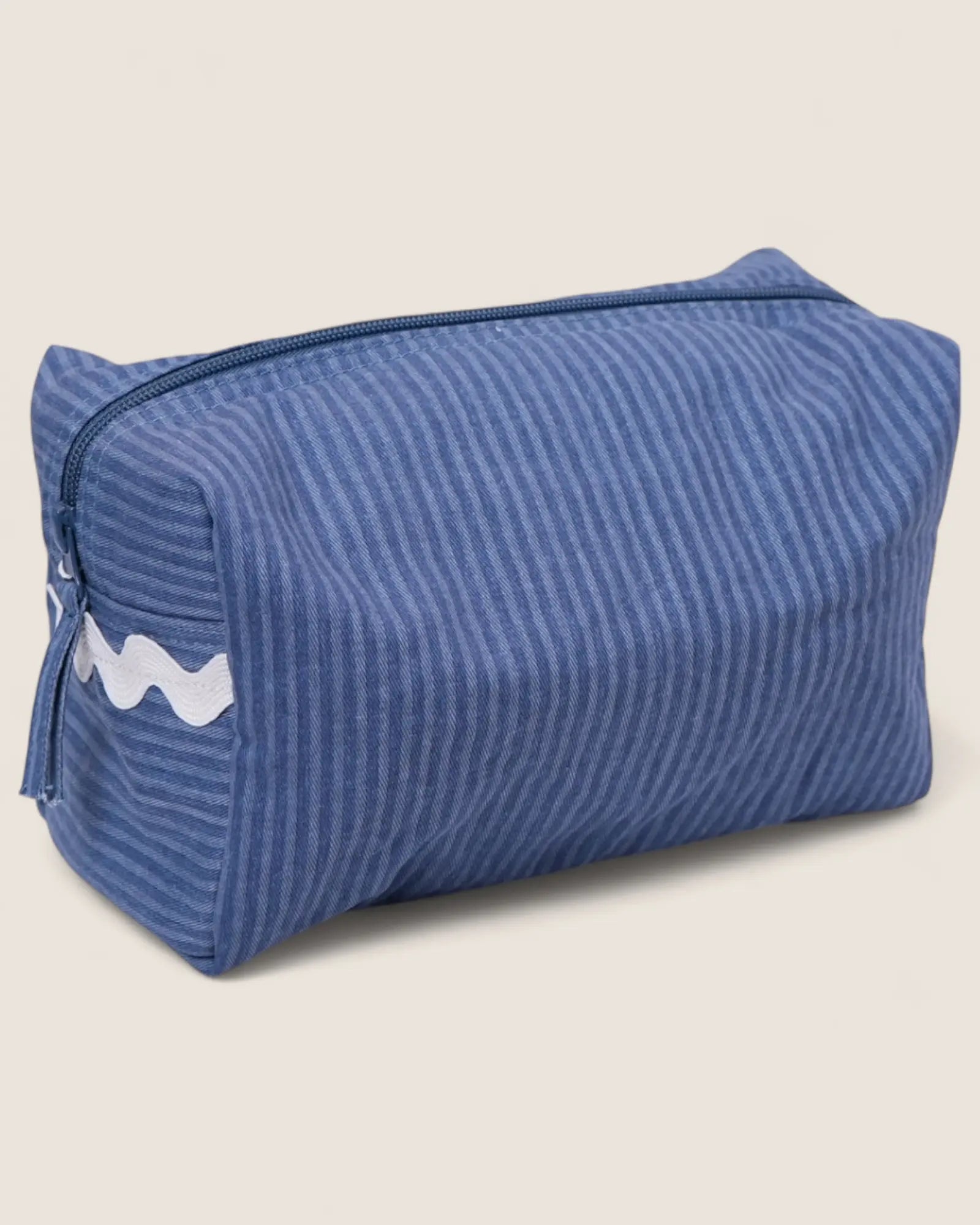 Blue striped toiletry bag with a white lwaved detail and blue zipper
