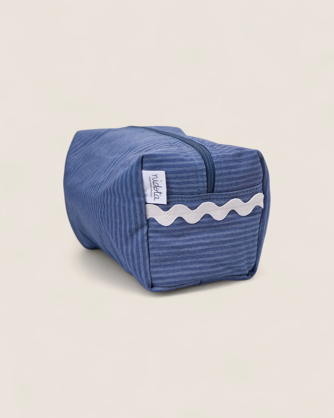 Blue striped toiletry bag with white waved detail and blue zipper