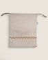 Striped pouch bag with wavy bottom edge on a light beige background