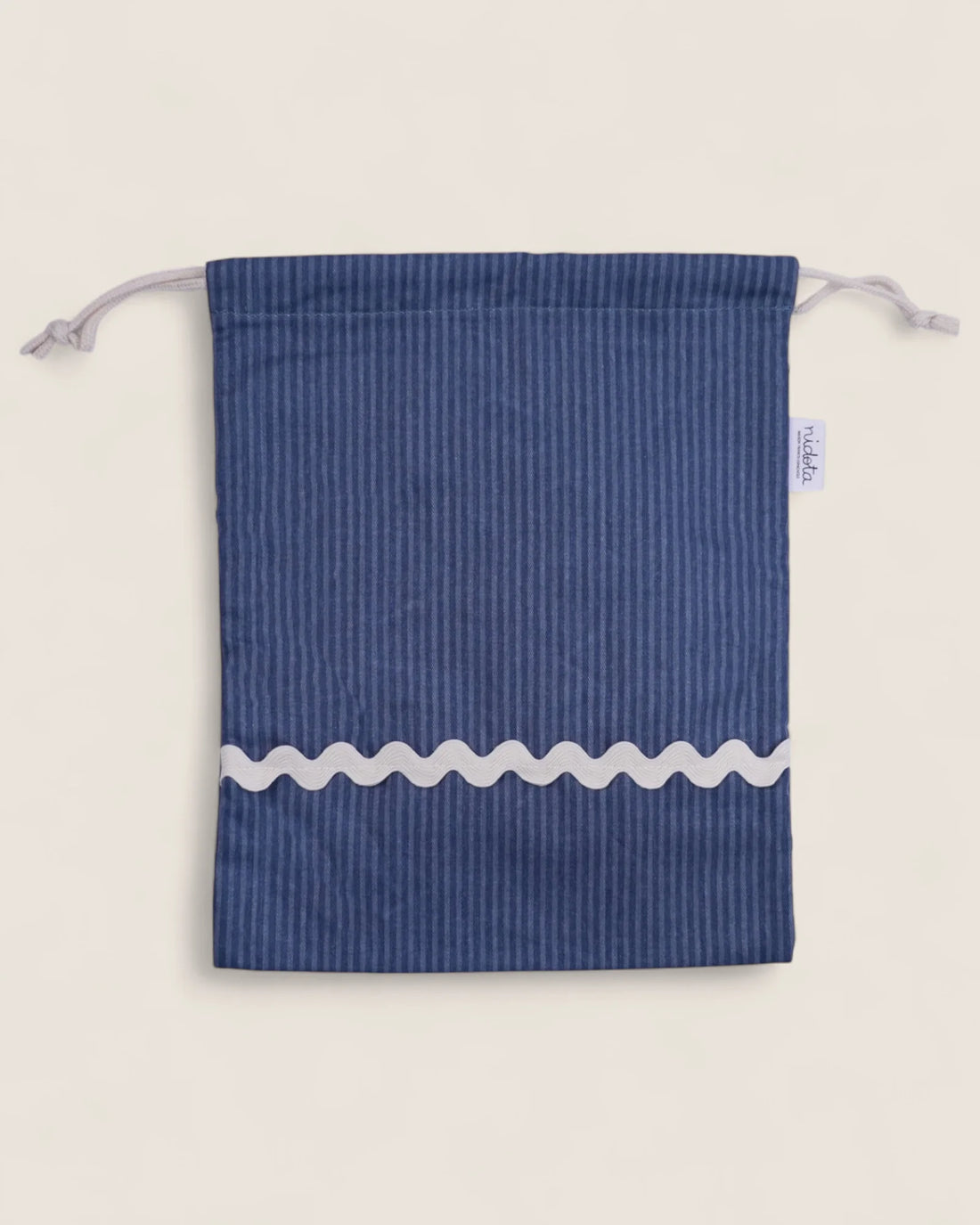 Blue striped pouch bag with white wavy line on a light beige background
